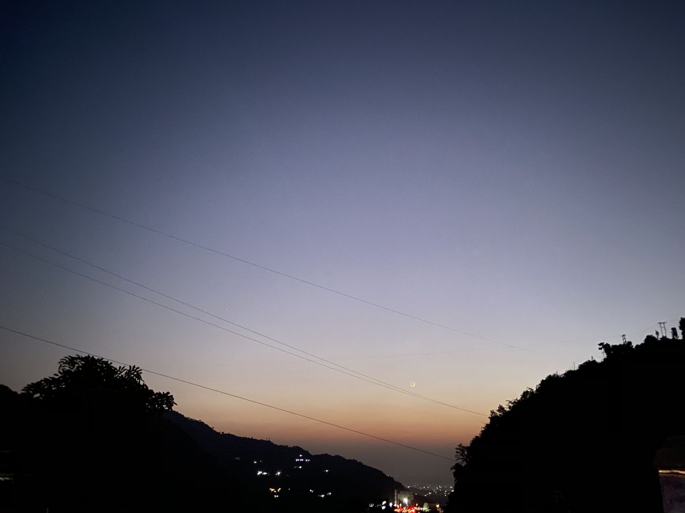 A crescent moon over hills at twilight
